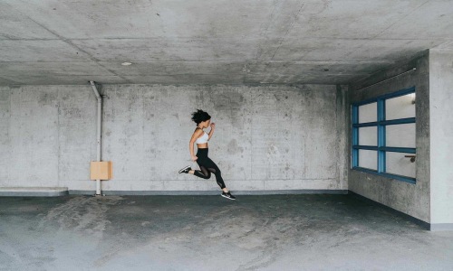 a woman jumping and doing active movements in a concrete area